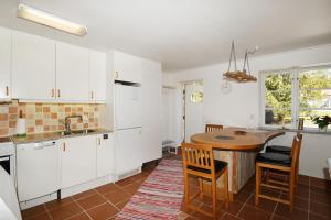 a kitchen with white cabinets and a wooden table at Cozy cottage on Gotland with sauna near salty baths in Lärbro
