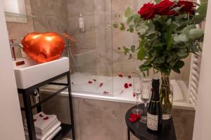 ein Badezimmer mit einer Vase aus Rosen und einer Badewanne in der Unterkunft Grand Hôtel Lévêque in Paris