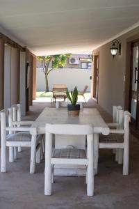 Micasa Sucasa Guesthouse في Lephalale: طاولة بيضاء وكراسي على الفناء
