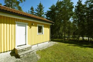 a yellow building with a white door and a yard at Cozy cottage on Gotland with sauna near salty baths in Lärbro
