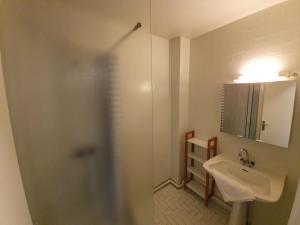 uma casa de banho com um lavatório e um chuveiro com um espelho. em Les apparts de l'atlantique em La Faute-sur-Mer