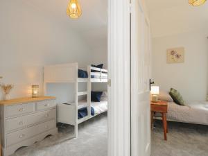 a bedroom with a bunk bed and a dresser and a bed at Carvannel Cottages in Camborne