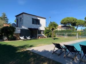 una casa con piscina e sedie accanto a una casa di Casa exclusiva, jardín y piscina privada a Calella de Palafrugell