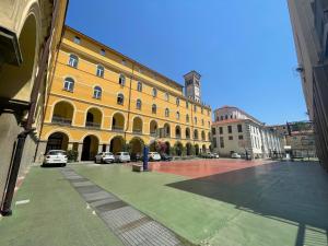 a large yellow building with a clock tower on a street at Casa Per Ferie San Giovanni Bosco in La Spezia