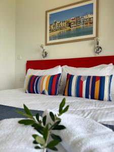 a bedroom with a bed with a red headboard and two pillows at The Beach House in Birżebbuġa
