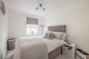 a white bedroom with a large bed and a window at Stylish 3-Bed House in Langley, Driveway Parking! in Langley Marish
