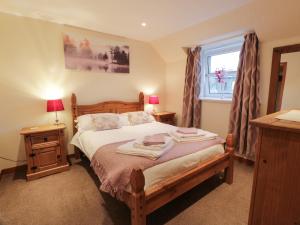 ein Schlafzimmer mit einem Bett mit zwei Tischen und einem Fenster in der Unterkunft Barley Cottage in Newton Stewart