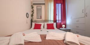 a bedroom with a white bed with red pillows at Chrysanthi's House in Ayios Kirikos