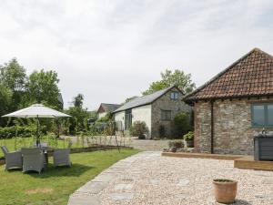 a patio with a table and chairs and an umbrella at The Hayloft in Honiton