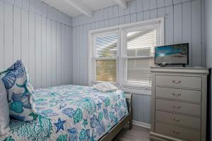 a bedroom with a bed with a television and a dresser at Anchor Haven Ocean Views in Oak Island