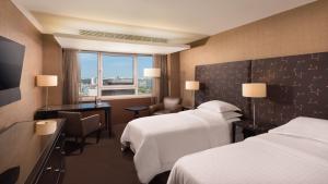 una camera d'albergo con 2 letti e una scrivania di Sheraton Lisboa Hotel & Spa a Lisbona