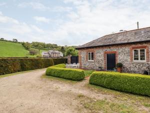 uma velha casa de pedra com sebes em frente em The Old Dairy Cottage em Dartford