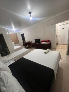 a bedroom with two beds and a living room at HOTEL CITYY in Ijuí