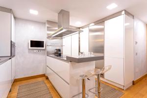 uma cozinha com paredes brancas e um balcão com bancos em Genteel Home Tetuán Sevilla em Sevilha