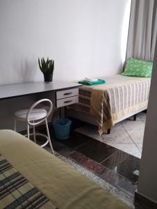 a bedroom with a desk and a bed and a chair at Hotel Pousada Beija Flor in Poços de Caldas