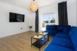 sala de estar con sofá azul y TV en Angolo Apartments, en Kaštela