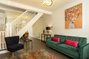 a living room with a green couch and a staircase at Sparkenhoe House in Hugglescote