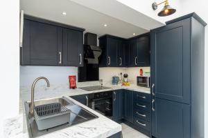uma cozinha com armários azuis escuros e um lavatório em Sparkenhoe House em Hugglescote