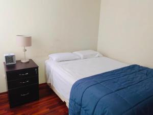 a bedroom with a bed and a night stand with a lamp at Hermoso Apartamento en el Centro de Trujillo in Trujillo