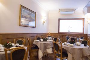 uma sala de jantar com mesas e cadeiras e uma foto na parede em Hotel Leopardi em Nápoles