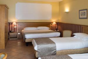 una camera d'albergo con due letti e due tavoli di Hotel Leopardi a Napoli