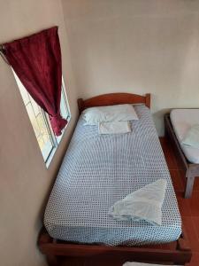 Habitación pequeña con cama y ventana en Guest House Nena en Moyogalpa