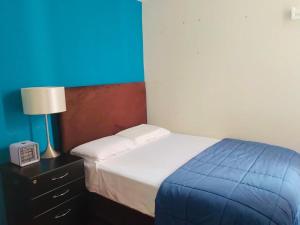 1 dormitorio con 1 cama y mesita de noche con lámpara en Hermoso Apartamento en el Centro de Trujillo, en Trujillo