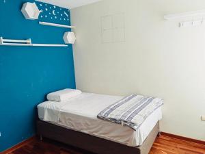 a small room with a bed with a blue wall at Hermoso Apartamento en el Centro de Trujillo in Trujillo