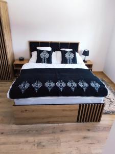 a bed with a black and white blanket and pillows at Bystry Domek in Kościelisko