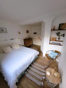 a bedroom with a white bed and a chair at La maison père camembert in Honfleur