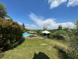 un jardín con piscina y sombrillas en Villa Ledonia, en Montaione