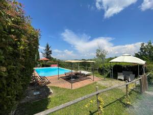 un patio trasero con piscina y sombrilla en Villa Ledonia, en Montaione