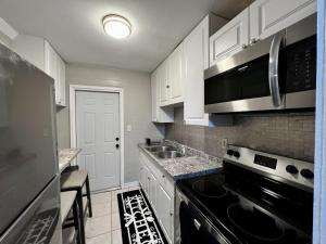 a kitchen with white cabinets and a black stove top oven at Cozy 2BR Home Near Shands Hospital, UF, and Downtown Gainesville in Gainesville