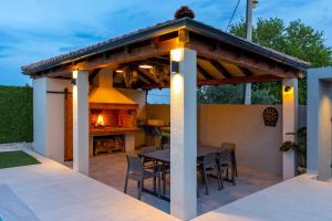 eine Pergola auf einer Terrasse mit einem Tisch und Stühlen in der Unterkunft Vintage House Bella Vita in Biograd na Moru