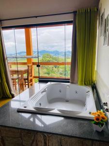 a bath tub in a bathroom with a large window at Chalés Terras Altas in Gonçalves
