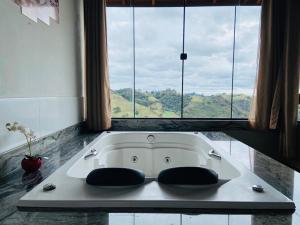 a bath tub with two chairs in front of a window at Chalés Terras Altas in Gonçalves