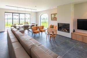 a living room with a couch and a tv and a table at Country house - 'T Reigershof in Veurne