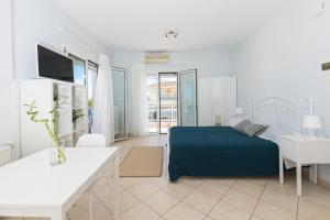 - une chambre blanche avec un lit bleu et une table dans l'établissement Urban Sea Side Apartments, à Thasos
