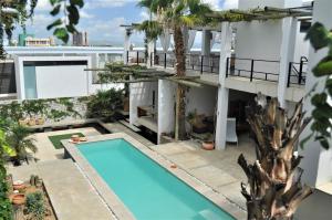 ein Apartmentgebäude mit einem Pool und Palmen in der Unterkunft Villa Vista Guesthouse, Windhoek, Namibia in Windhoek