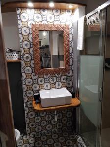 La salle de bains est pourvue d'un lavabo et d'un miroir. dans l'établissement Il Girasole Storico, à Pitigliano