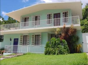 Casa verde grande con balcón blanco en Casa Mia Guest House en Rincón