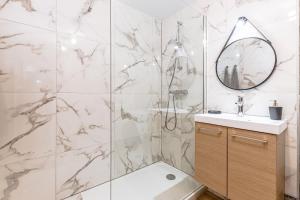 een badkamer met een douche, een wastafel en een spiegel bij Home Design Hayange in Hayange