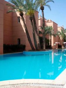- une piscine bordée de palmiers en face d'un bâtiment dans l'établissement Riad Qariya siyahiya, à Marrakech