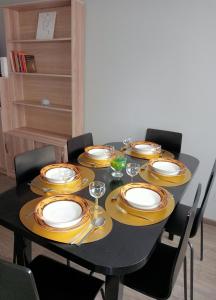 a table with yellow and white plates and wine glasses at Apartament Queen in Malbork
