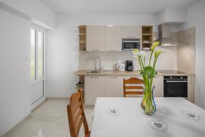 eine Küche mit einem Tisch und einer Blumenvase darauf in der Unterkunft Apartment Kazalac Green Oasis in Poreč + 16 Fotos