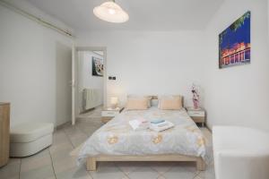 ein weißes Schlafzimmer mit einem Bett und einem Badezimmer in der Unterkunft Apartment Kazalac Green Oasis in Poreč