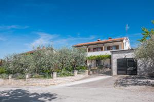 ein Haus mit einem Zaun vor einer Einfahrt in der Unterkunft Apartment Kazalac Green Oasis in Poreč