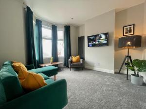 a living room with a green couch and a tv at 3 Bedroom Spacious House in Cardiff in Cardiff