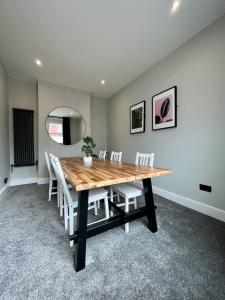 a dining room with a wooden table and white chairs at 3 Bedroom Spacious House in Cardiff in Cardiff