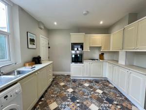 a kitchen with white cabinets and a tile floor at 3 Bedroom Spacious House in Cardiff in Cardiff